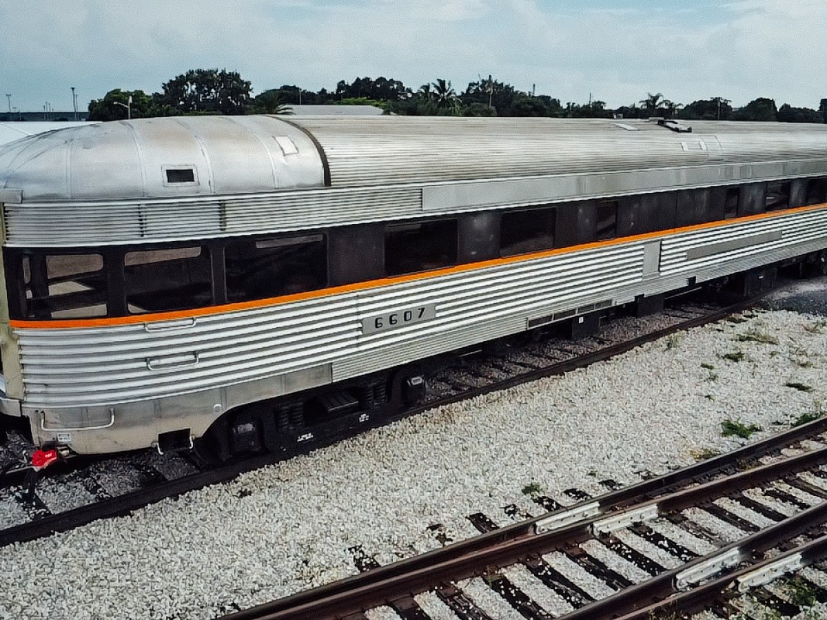 Silver vintage train car with orange stripe on railway tracks