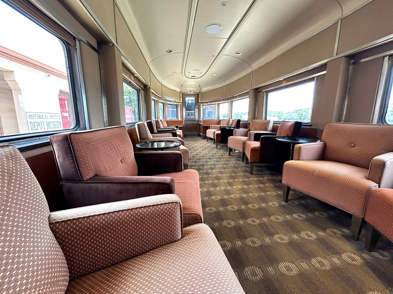 Luxurious train interior with brown seating and large windows.
