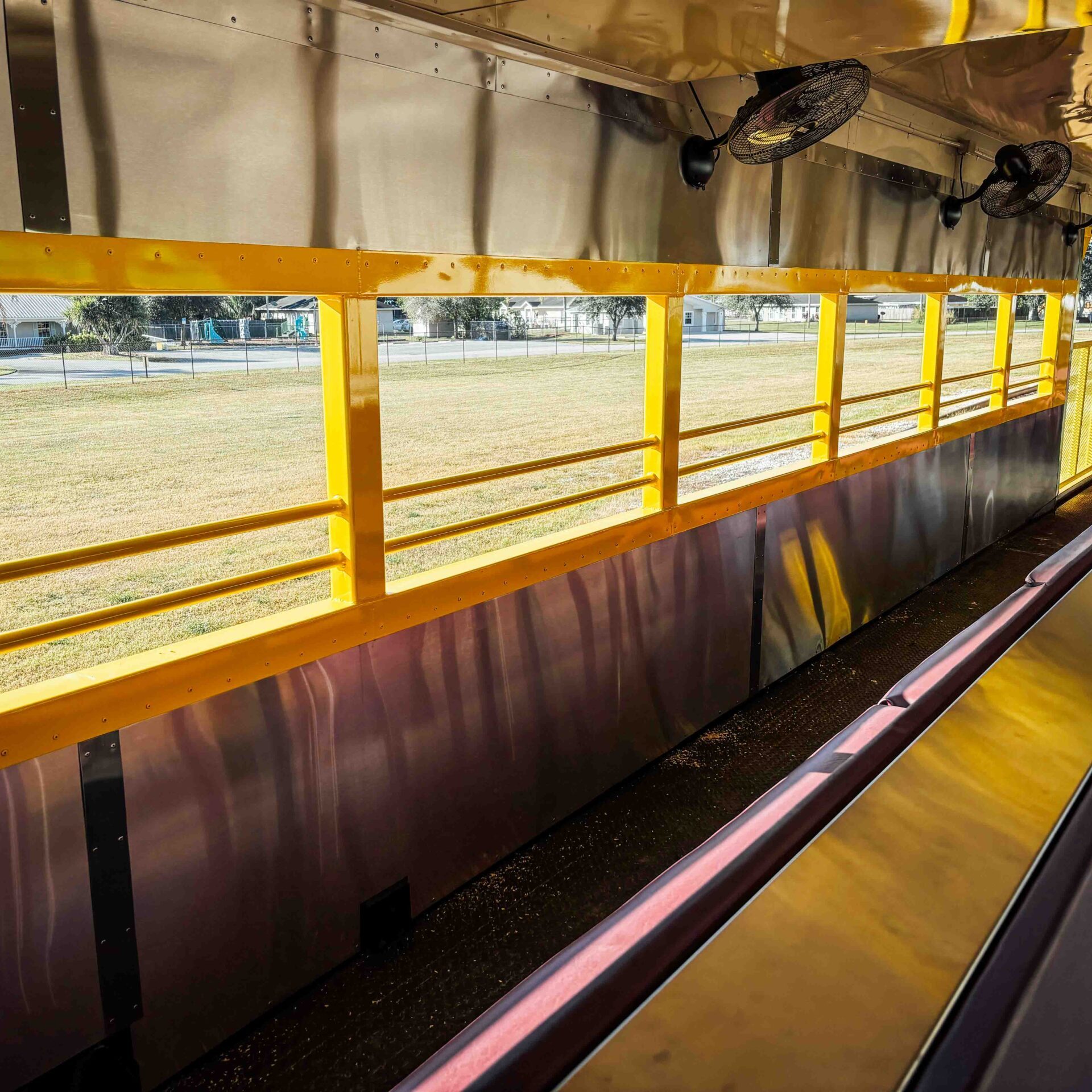 Interior of open-air train car with yellow railings and metal ceiling.