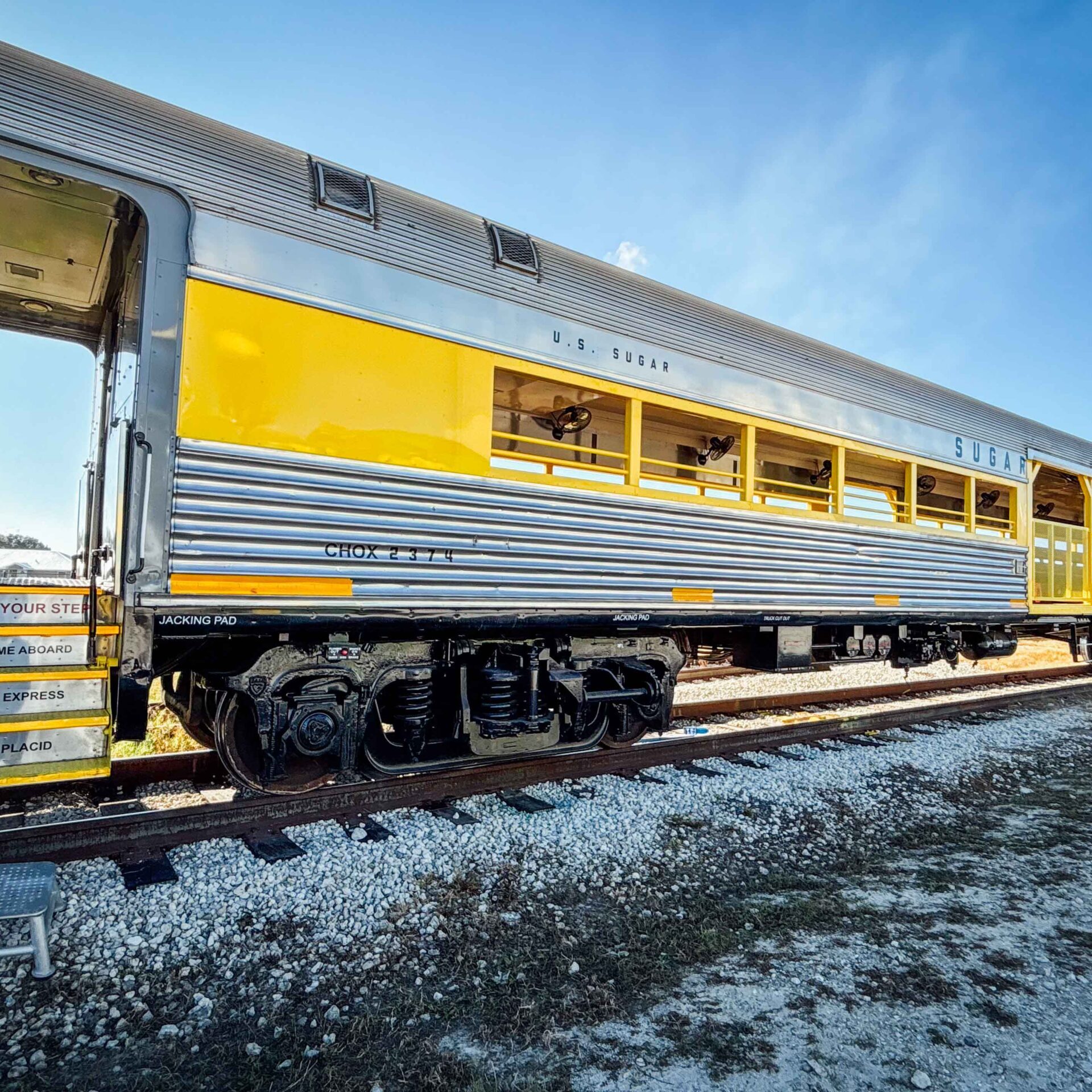 Vintage train car with yellow and silver exterior parked on tracks.
