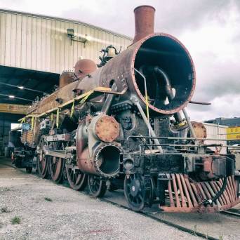 An old steam locomotive being repaired in a large workshop.