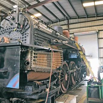 Vintage steam locomotive under restoration in a workshop.