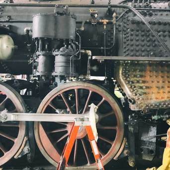 Close-up of a vintage train's wheel and mechanical parts.