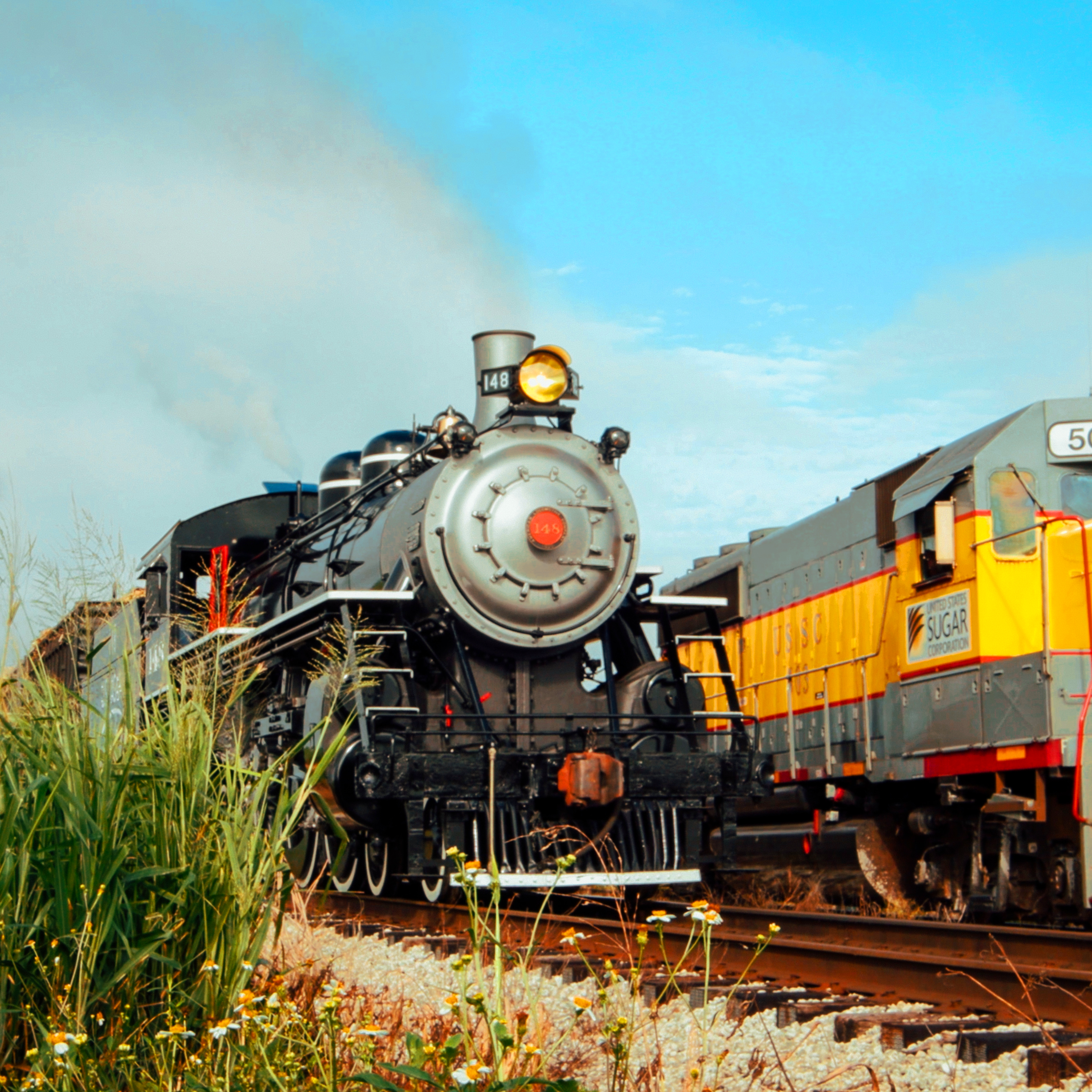 Steam locomotive and diesel engine on parallel tracks.