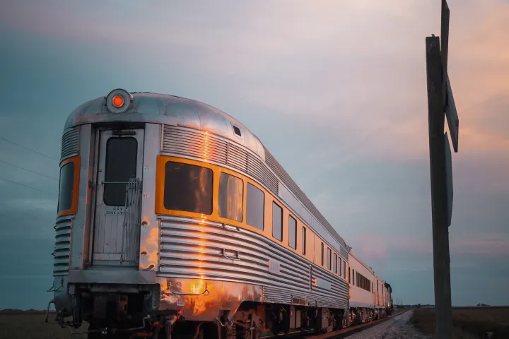 Retro train on tracks during sunset with cloudy sky.