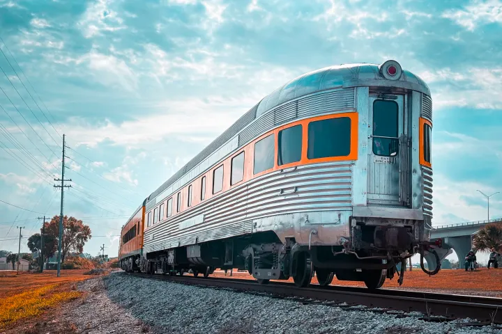 Vintage silver train on tracks under a partly cloudy sky.