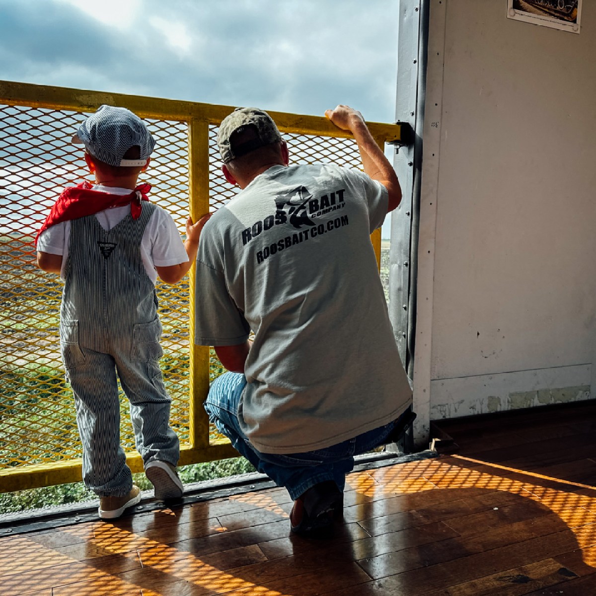 Man and child in overalls looking out from a train car.