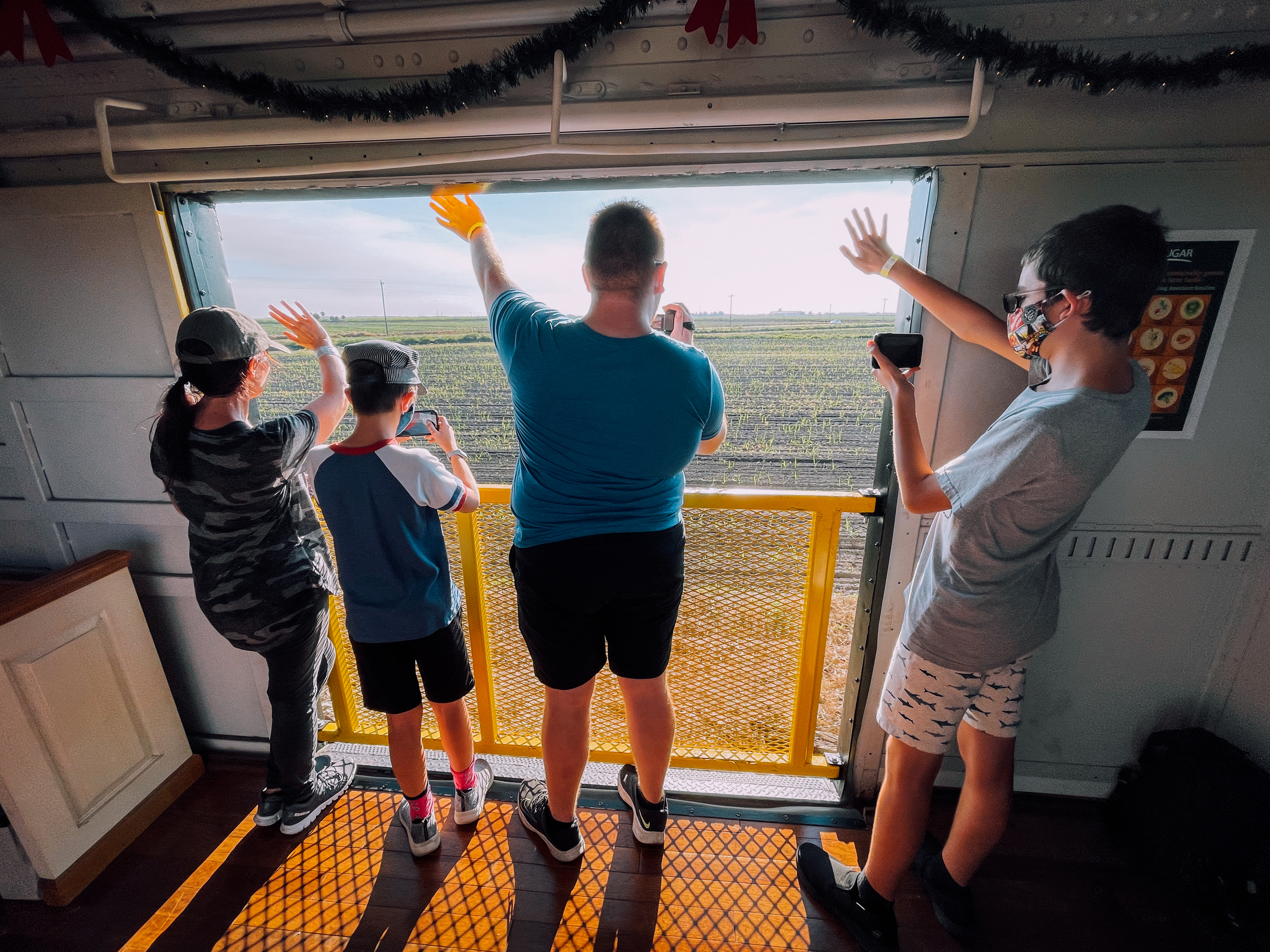 Passengers enjoying open air viewing platform aboard Sugar Express train while traveling through Florida farmland