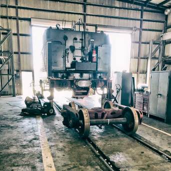Train carriage in repair workshop with exposed wheels and tools.