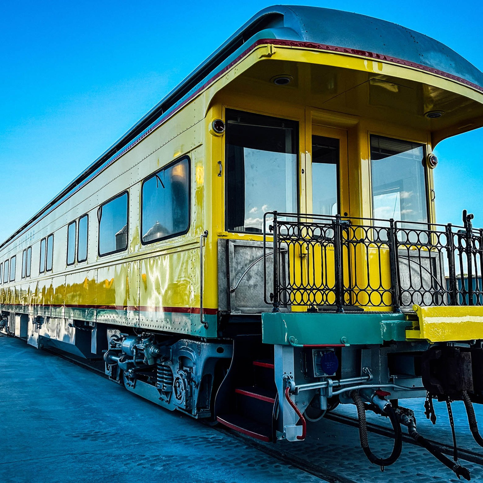 Vintage yellow train car on a sunny day with blue sky.