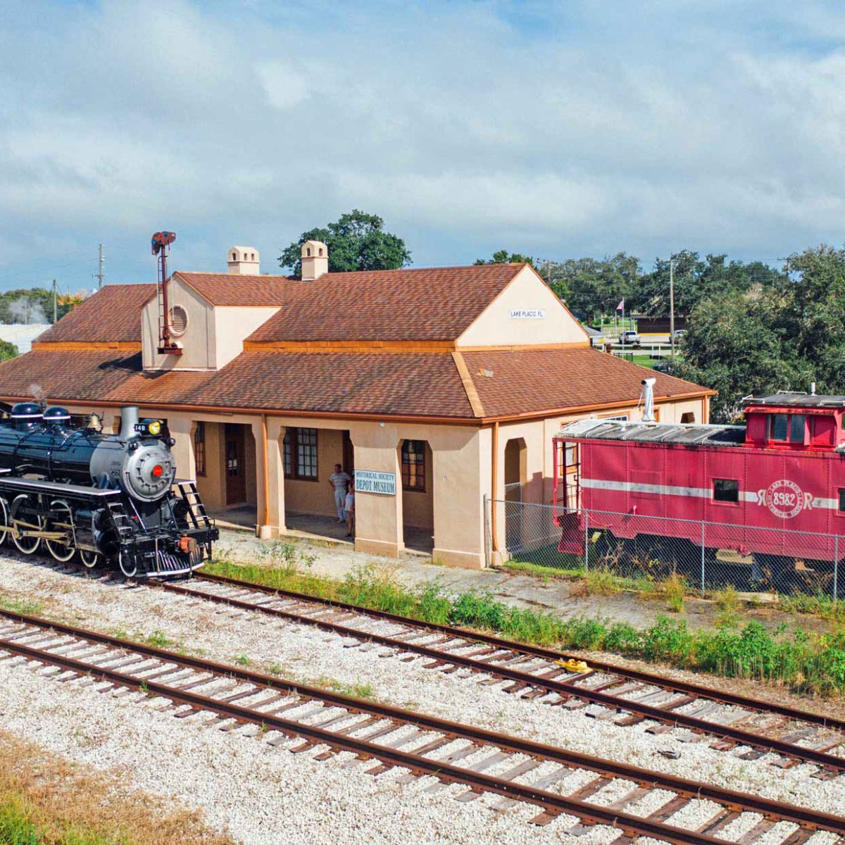 Vintage train and caboose at historic station with blue sky.