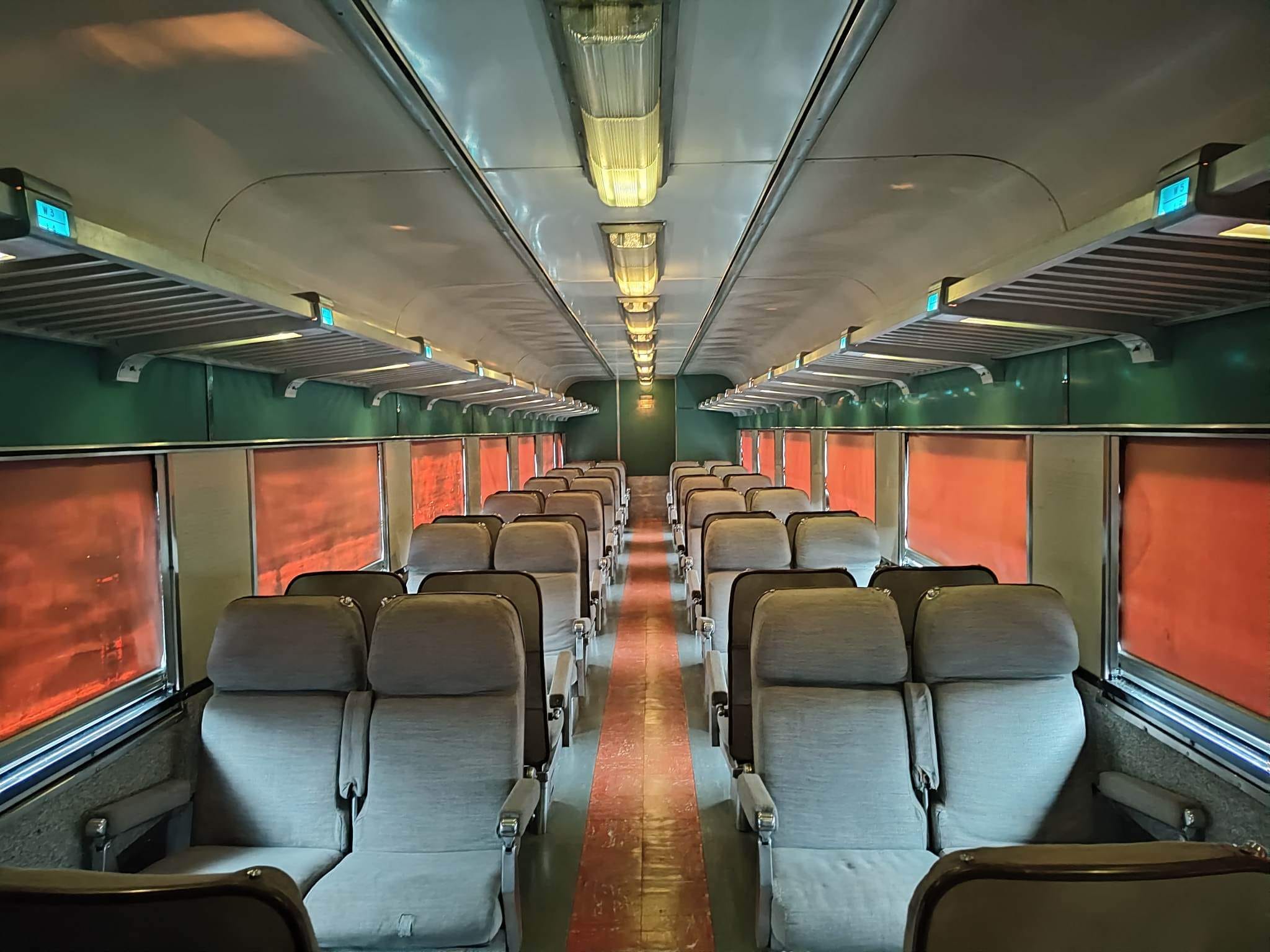 Vintage passenger coach interior aboard Sugar Express train with rows of gray reclining seats and large windows