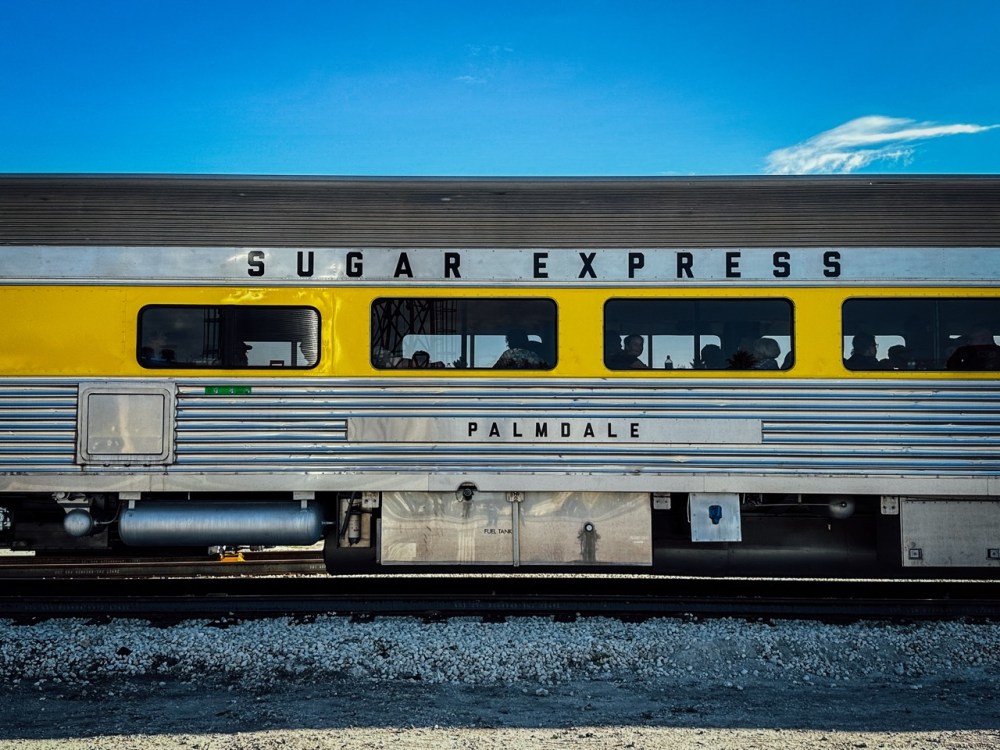 Yellow and silver passenger train labeled 'Sugar Express' at a station.