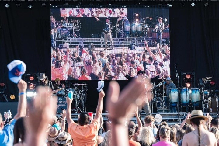 Large outdoor concert with crowd and musicians on stage.